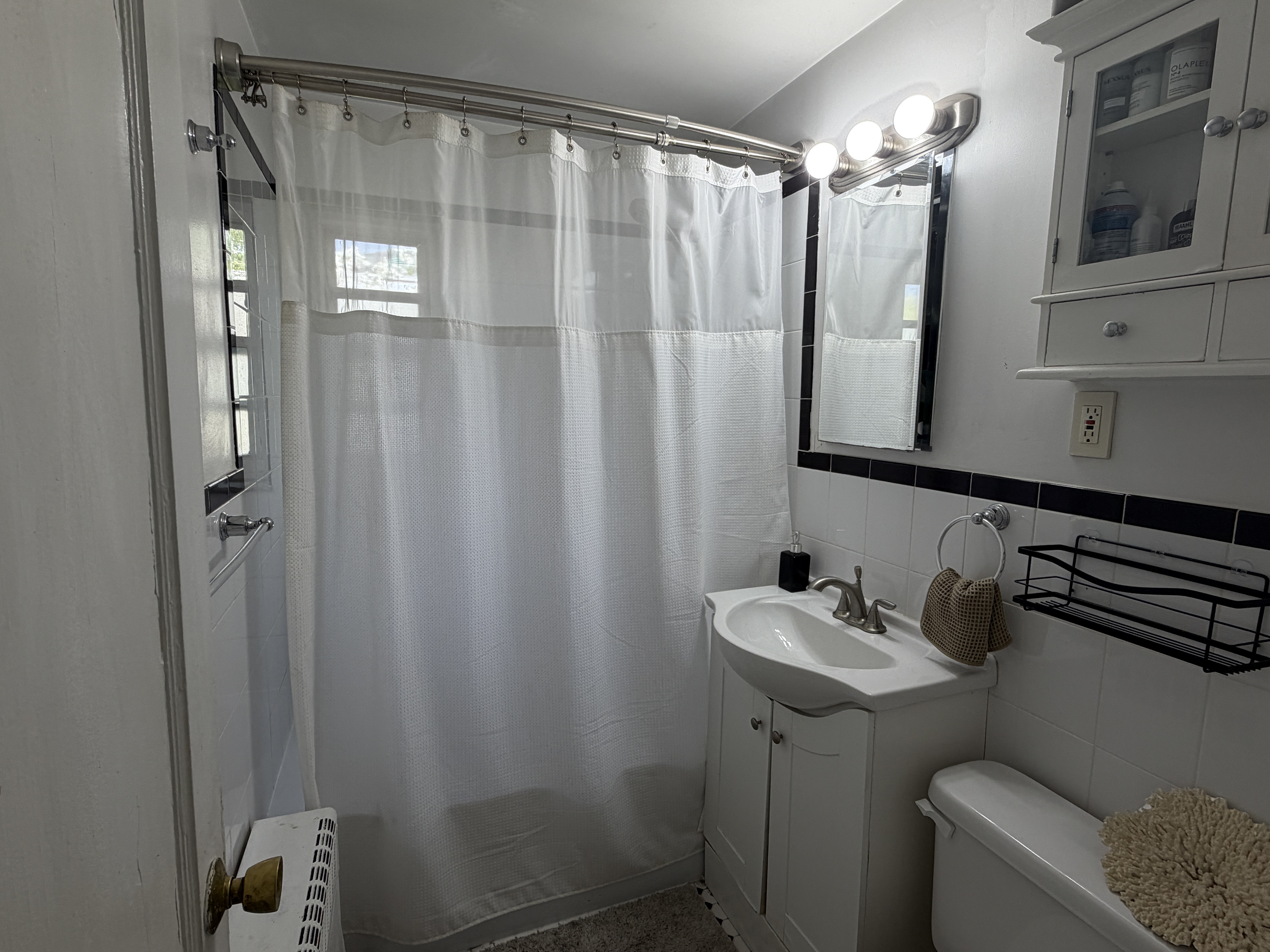 Full bathroom with tub/shower, vanity, and classic black-and-white tile